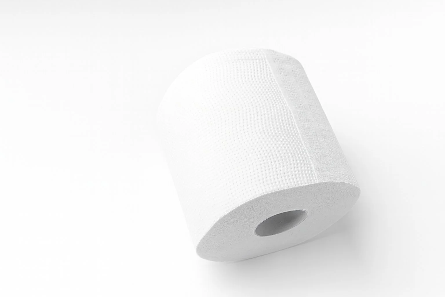 A roll of white toilet paper with textured surface, placed on a white background.