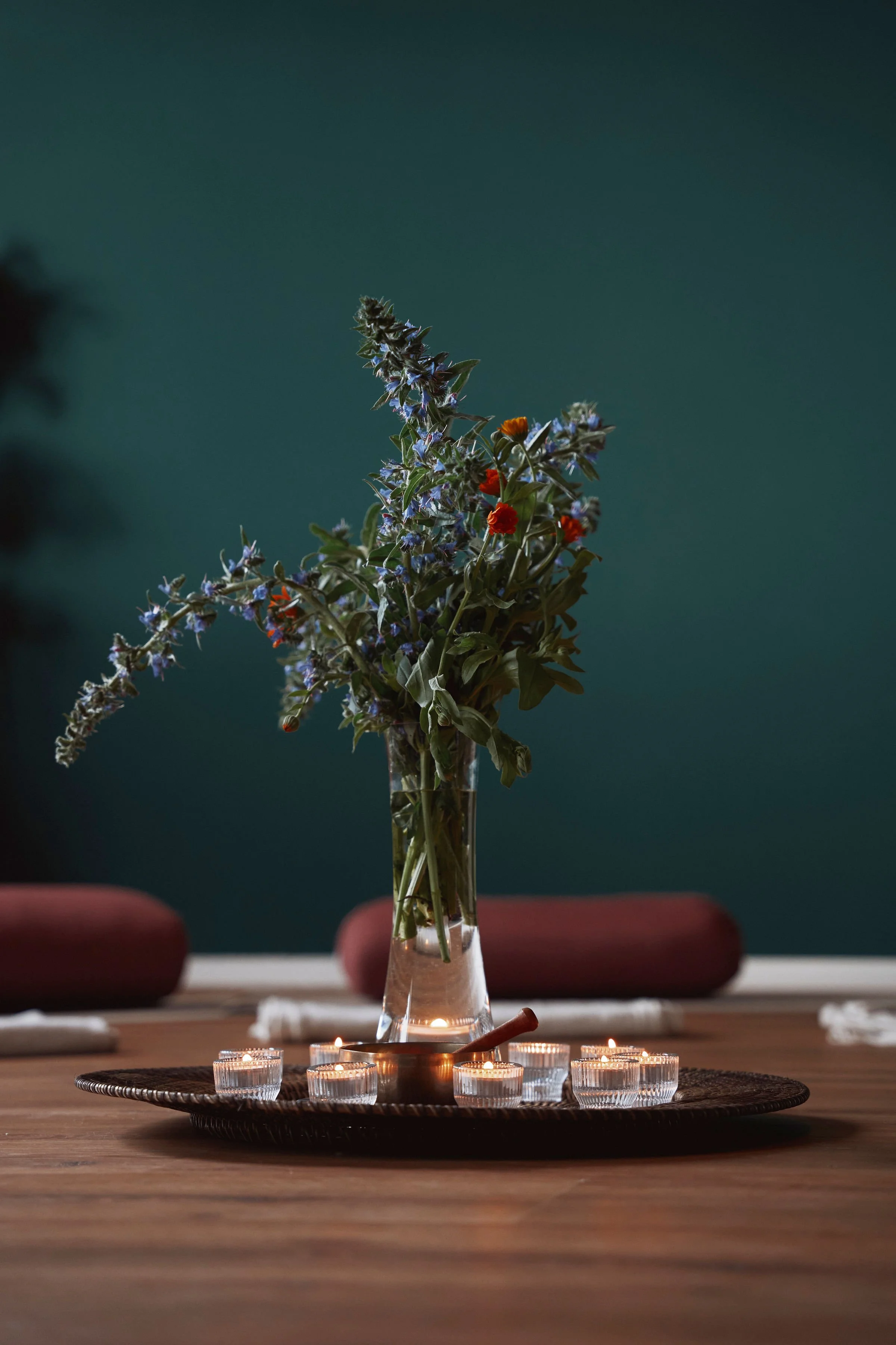 Blumenvase im Brehm. Dunkelgrüne Wände und rote Bolster, um sich geerdet und ruhig zu fühlen.