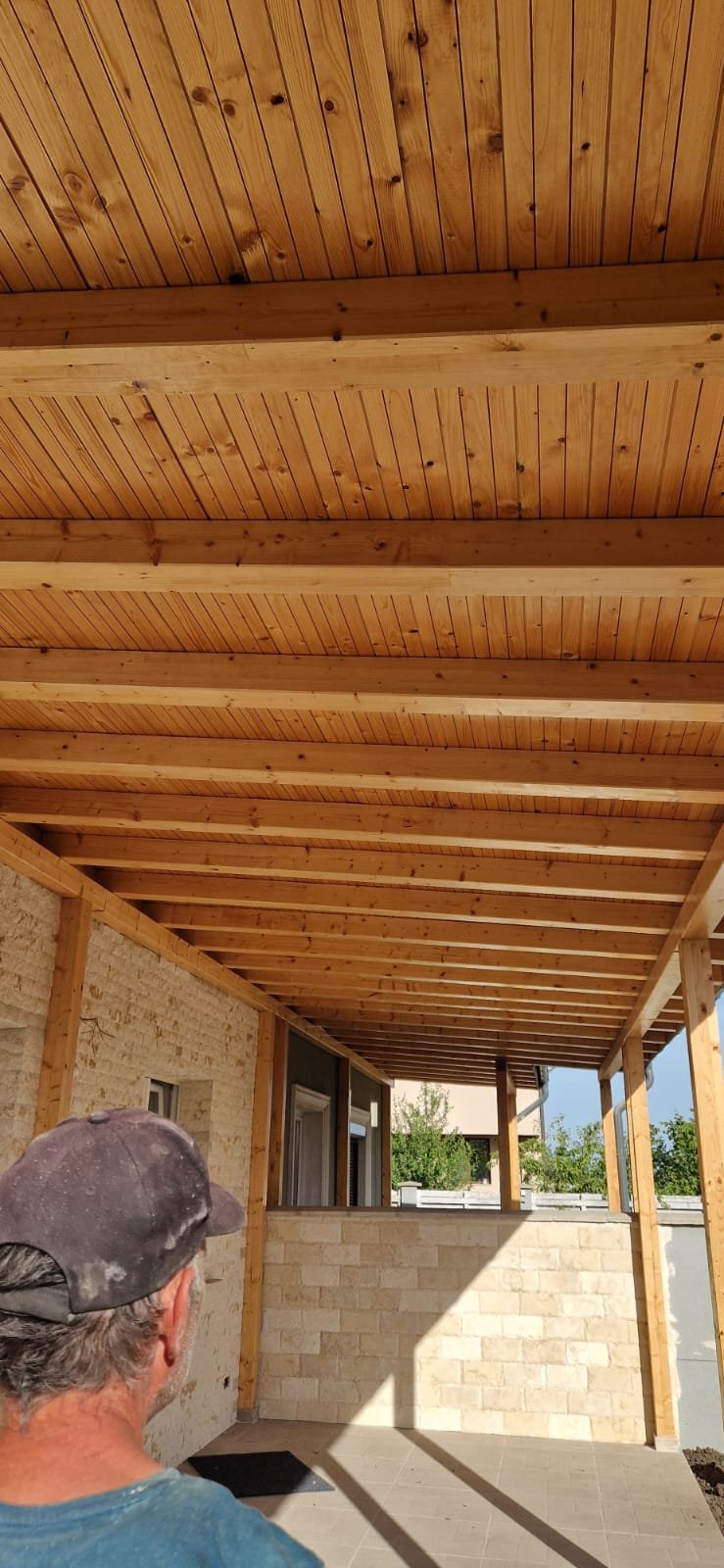 Construction site with unfinished wooden ceiling framework and a worker wearing a cap.
