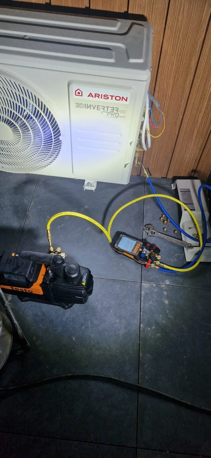 Air conditioning unit with tools and gauges connected, indicating a service or repair process.