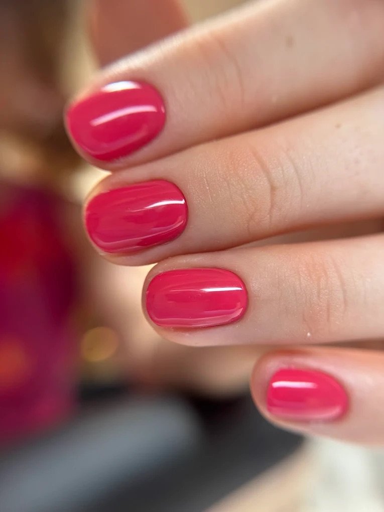 Close-up of a hand with neatly manicured nails painted in glossy pink polish.