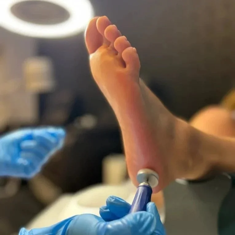 Close-up of a foot being injected with anesthesia by a healthcare professional wearing blue gloves in a clinical setting.