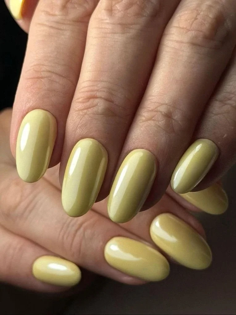 Close-up of a hand with yellow, glossy painted nails.