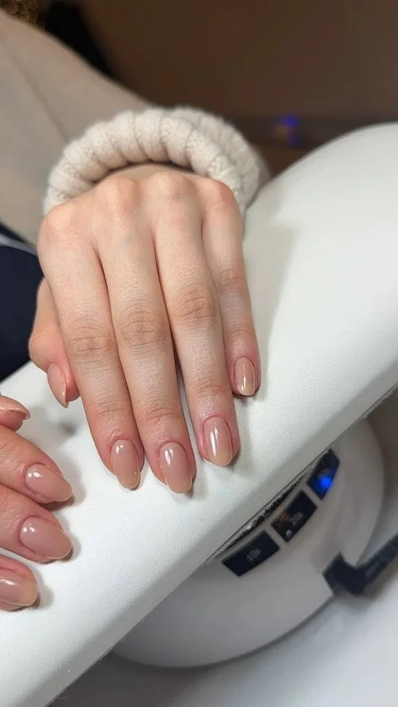 Close-up of a woman's hand with freshly manicured nails resting on a white surface.