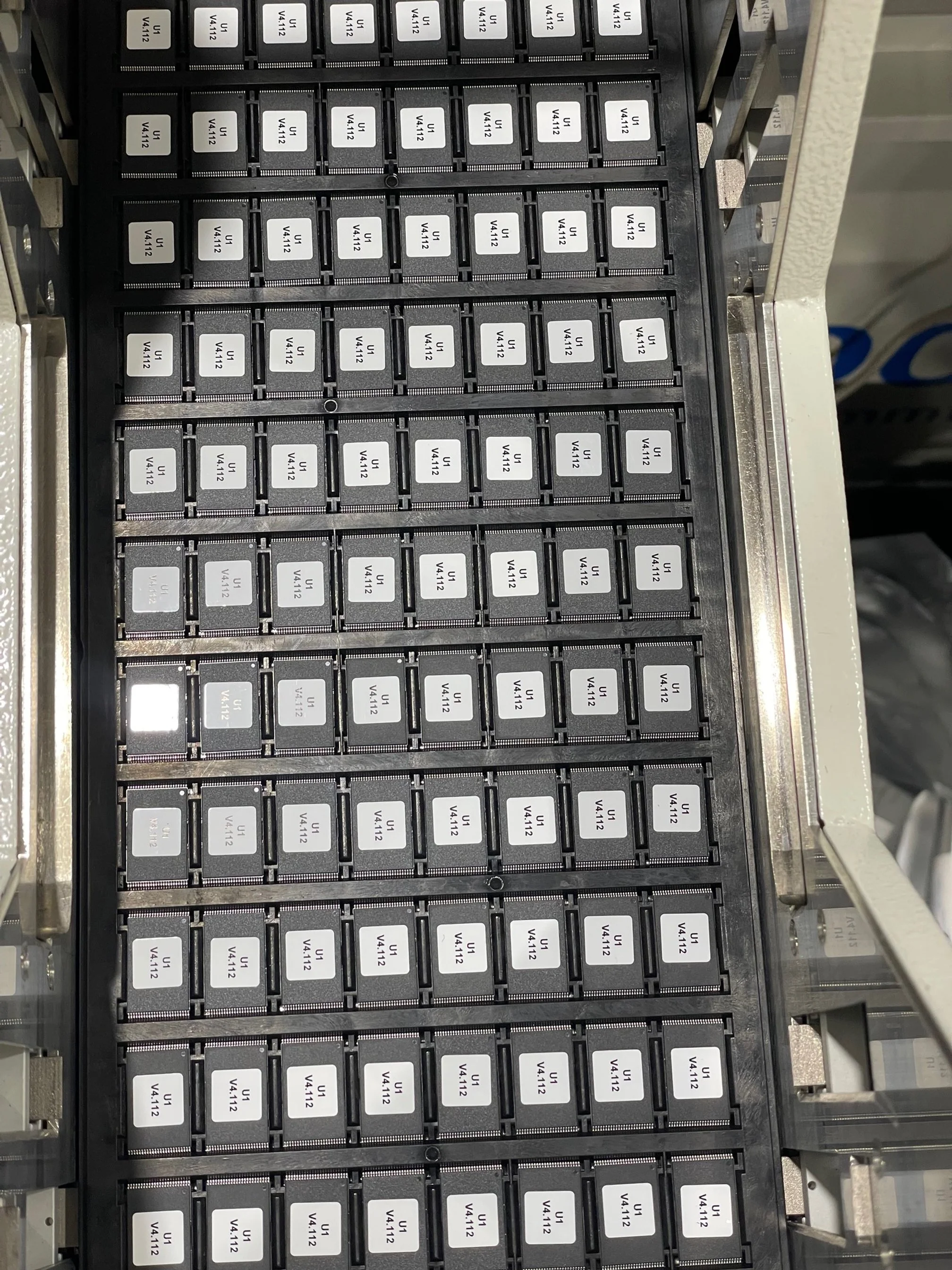 A grid of electronic components, labeled with codes like U1, V4,112, arranged on a black tray.