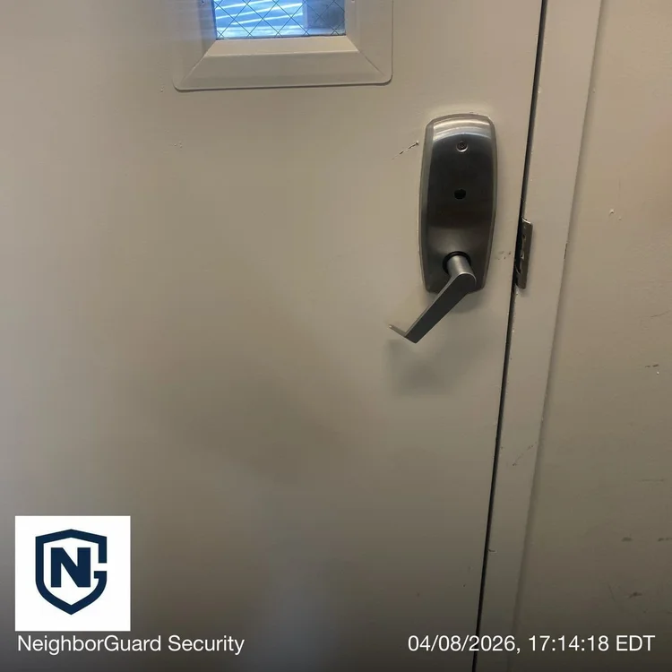 Time-stamped audit photo of a building rear door with the lever handle stuck in the down position