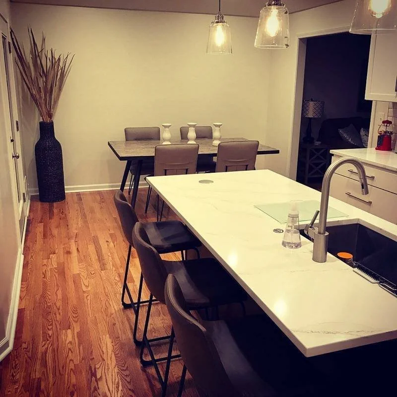	
Modern kitchen with custom white cabinets, a white marble countertop, stainless steel appliances, and hardwood flooring.
