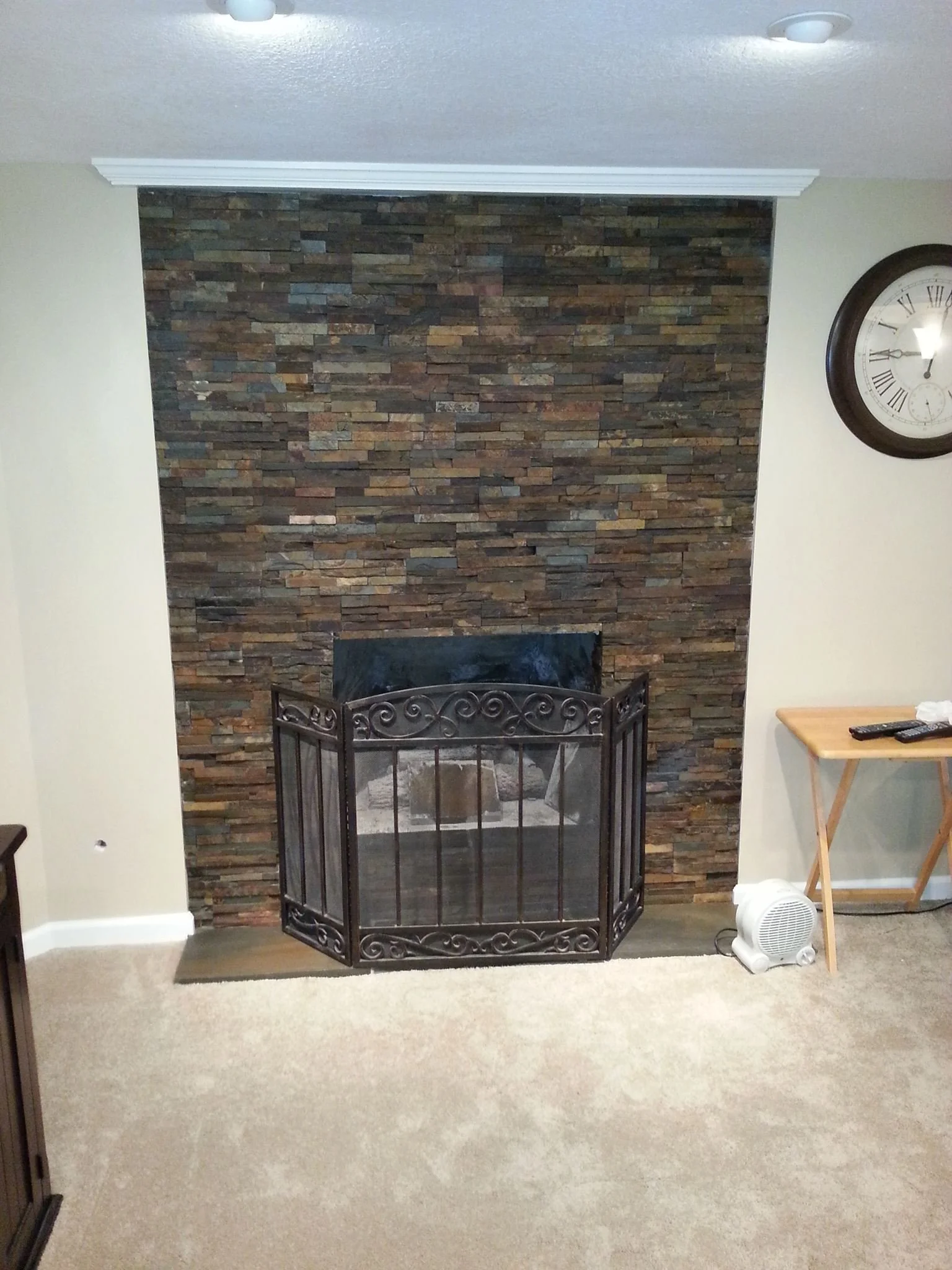 Living room with a stone fireplace and black metal fire screen
