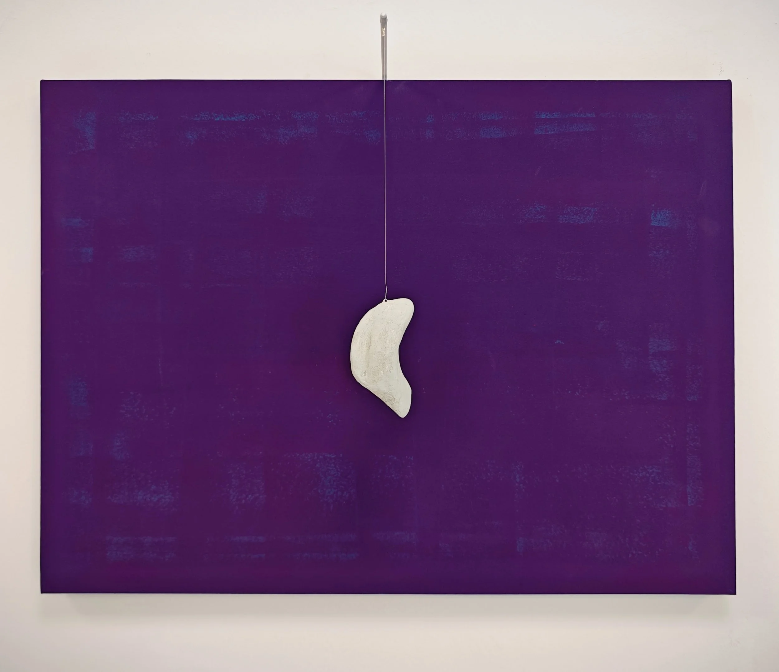 Una composizione artistica con uno sfondo viola e un oggetto a forma di mezzaluna bianca sospeso da un filo