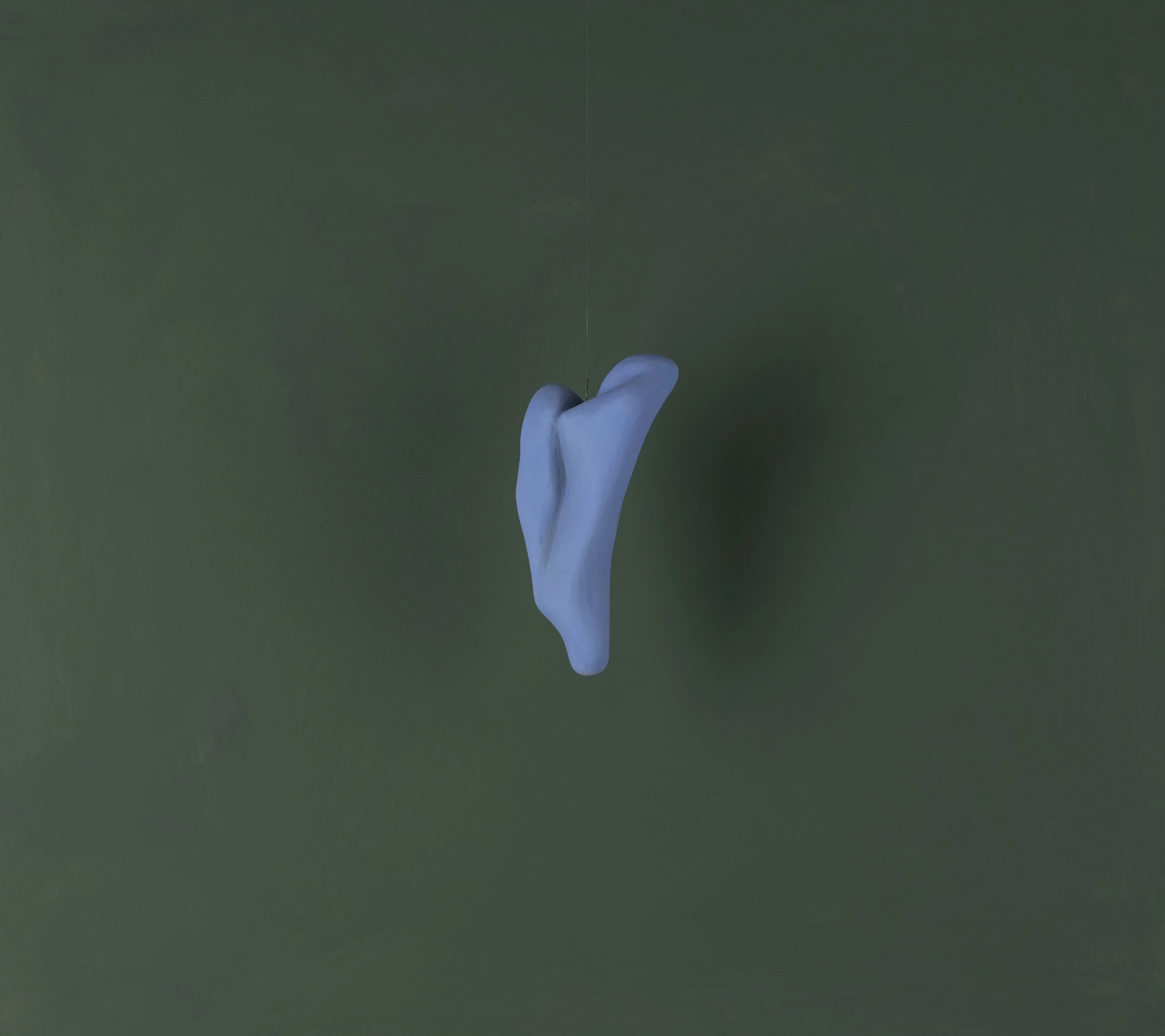 Forma astratta di colore blu sospesa in aria su sfondo verde