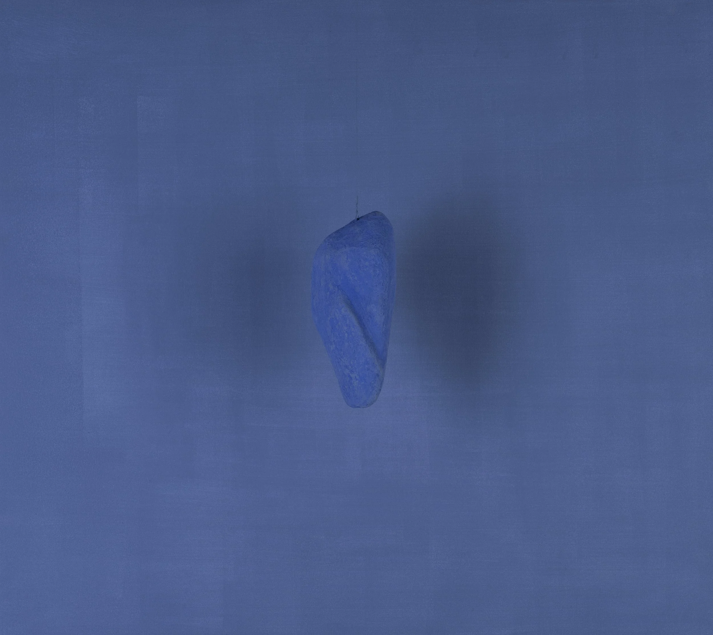 Una pietra blu posizionata su uno sfondo blu uniforme.