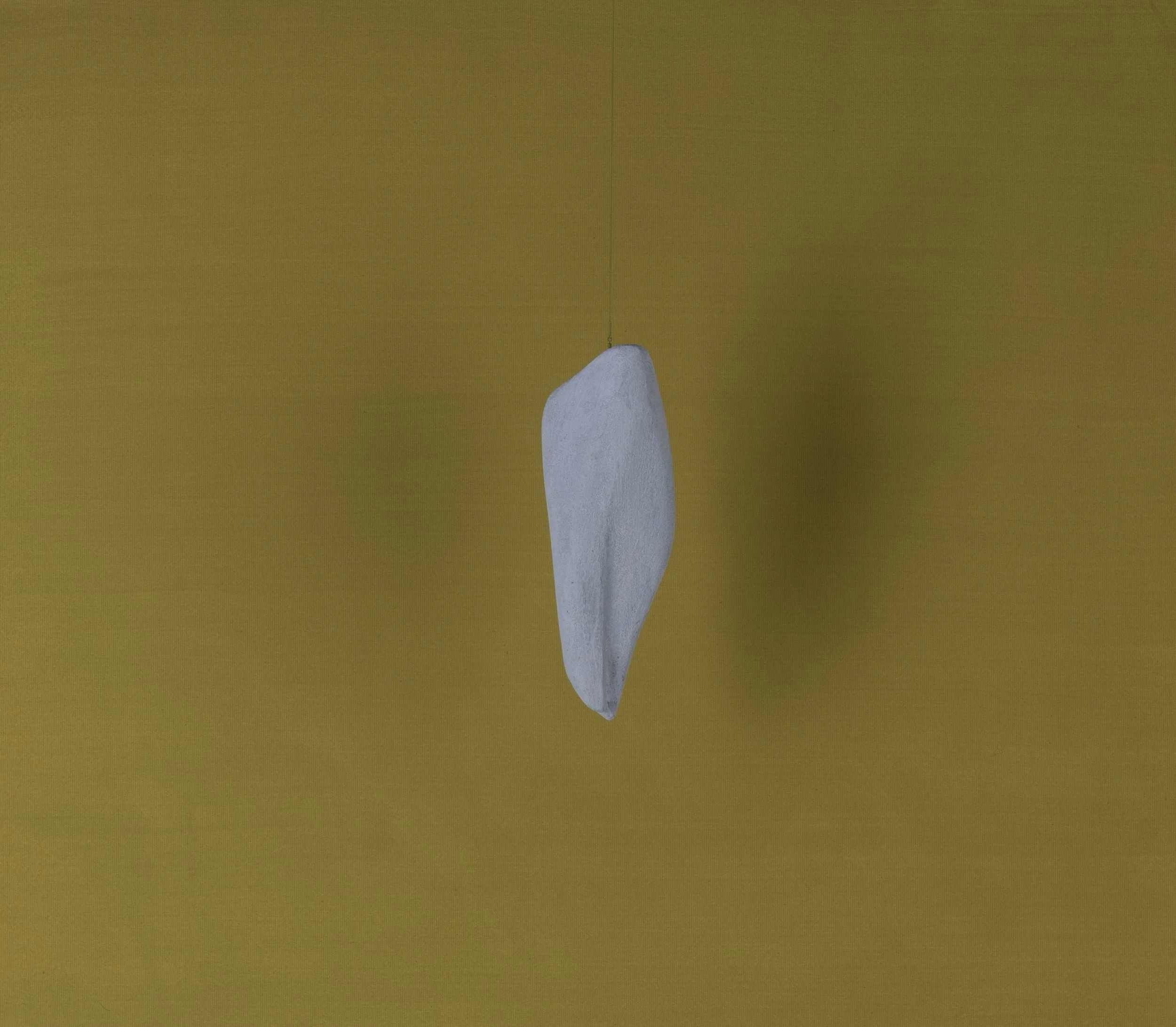 Sospensione decorativa di un piccolo scoglio bianco su sfondo giallo.