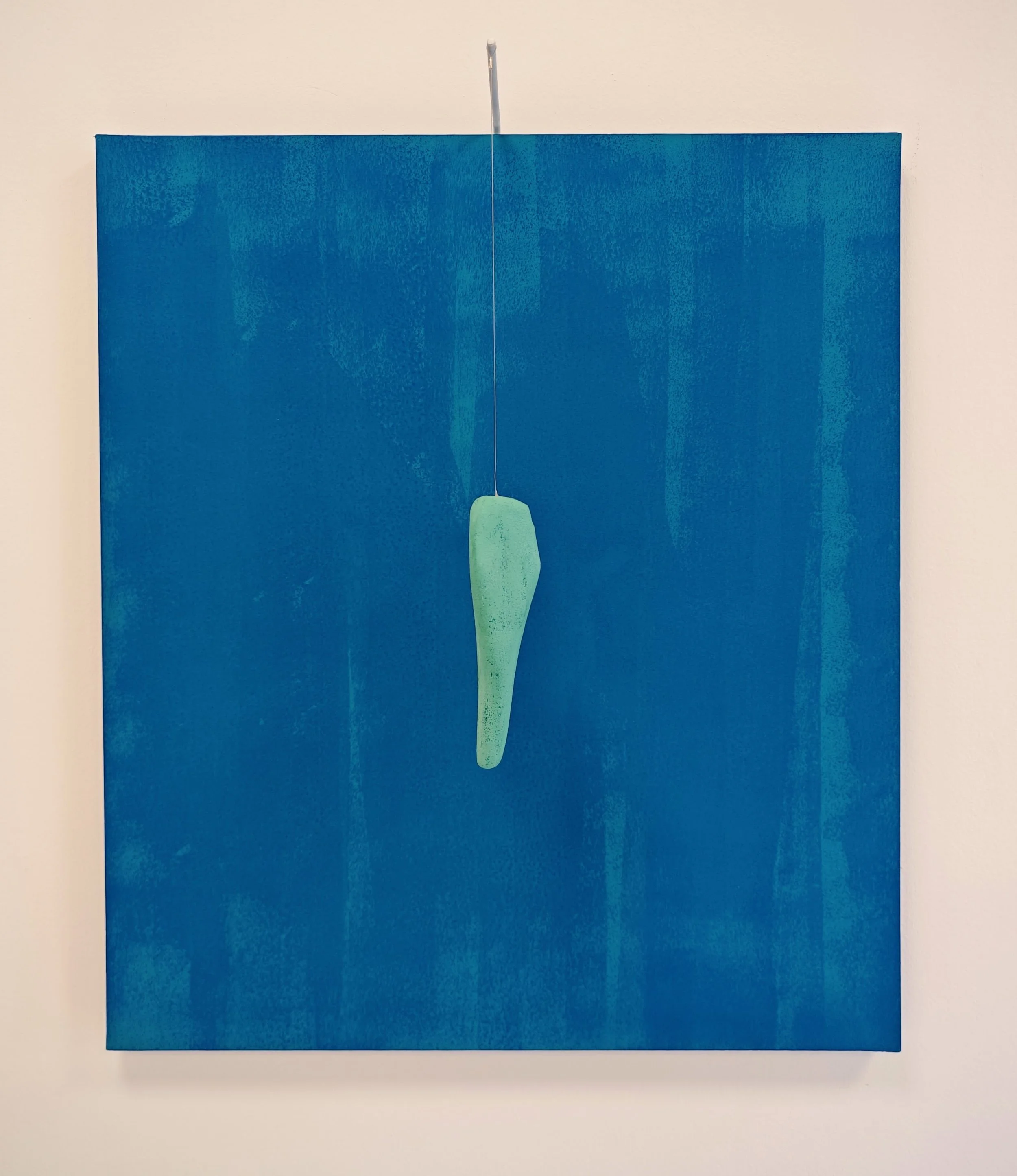 Un'opera d'arte astratta con una forma verde sospesa su uno sfondo blu