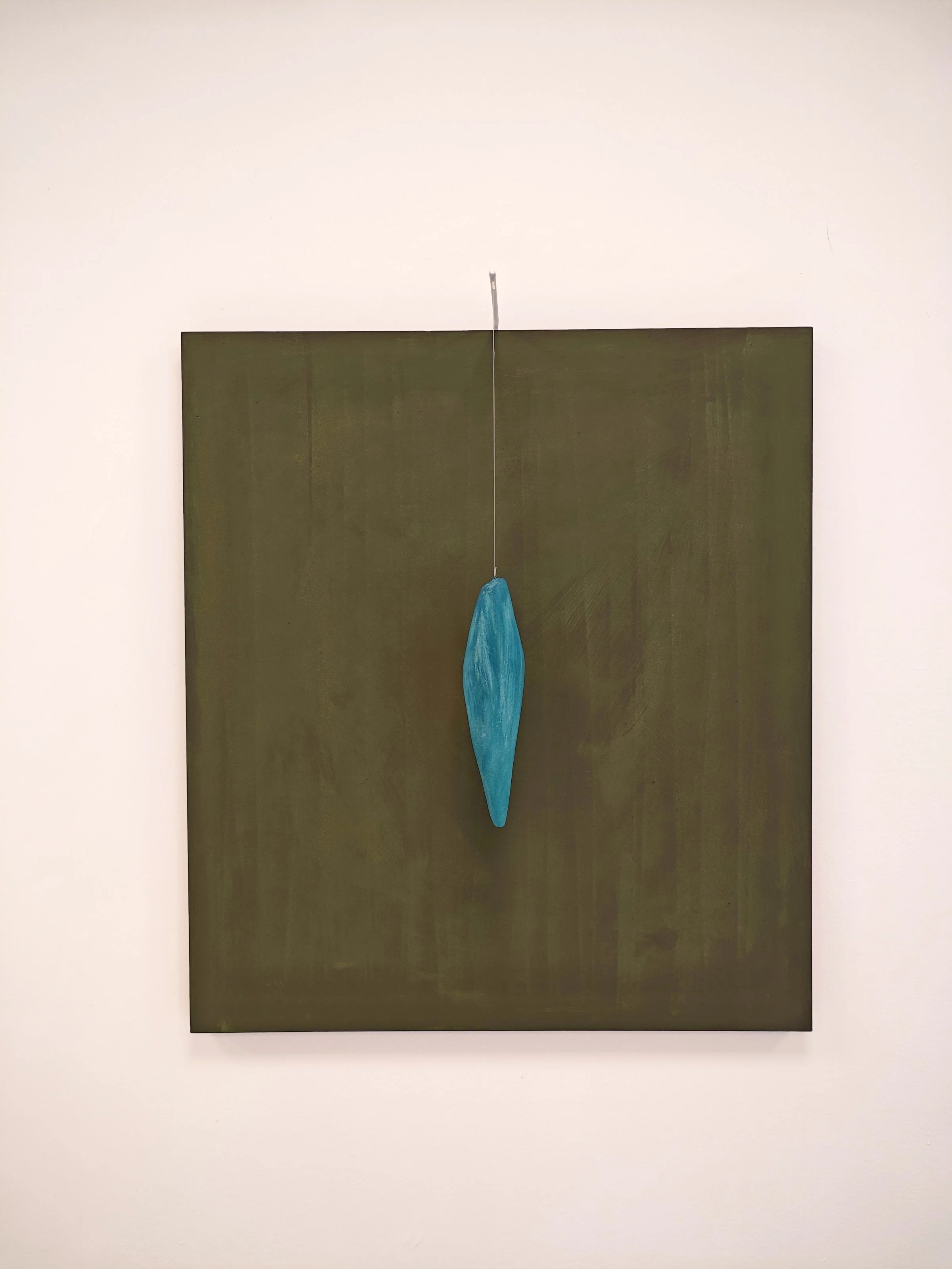 Dipinto astratto con una forma blu sospesa, su sfondo verde e cornice bianca.