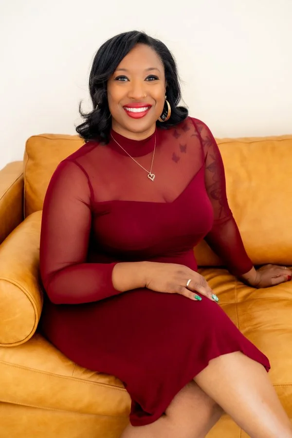 Woman smiling in a red dress in a bright, welcoming setting.