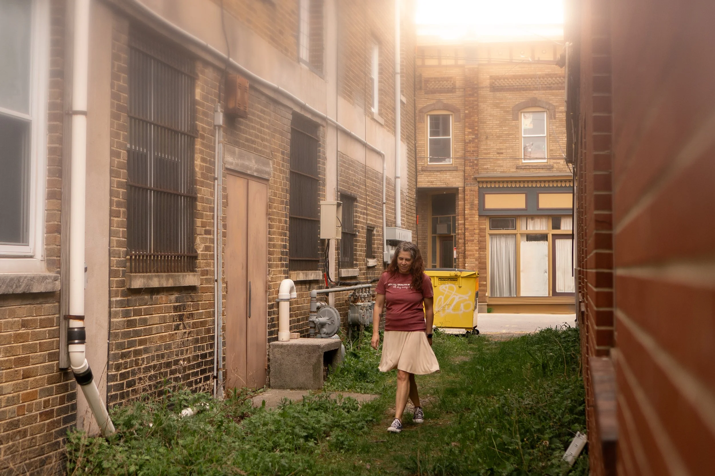 Licensed therapist Alesia Dumas providing attachment-focused counseling for adults walking in a grassy area between two older buildings in Philipsburg, PA.