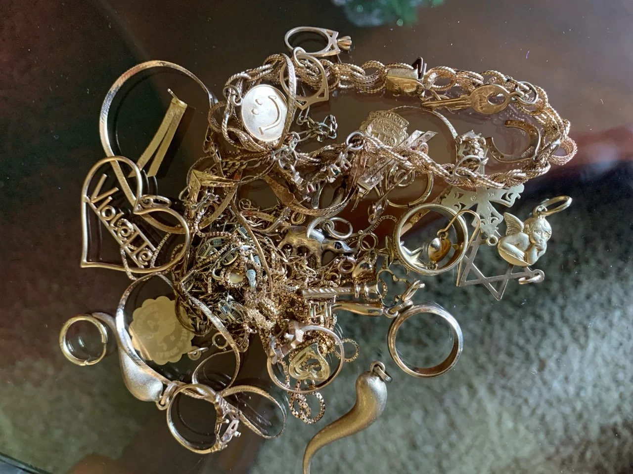 Un tas de bijoux en métal, comprenant des colliers, des bracelets et des anneaux, dispersés sur une surface sombre.