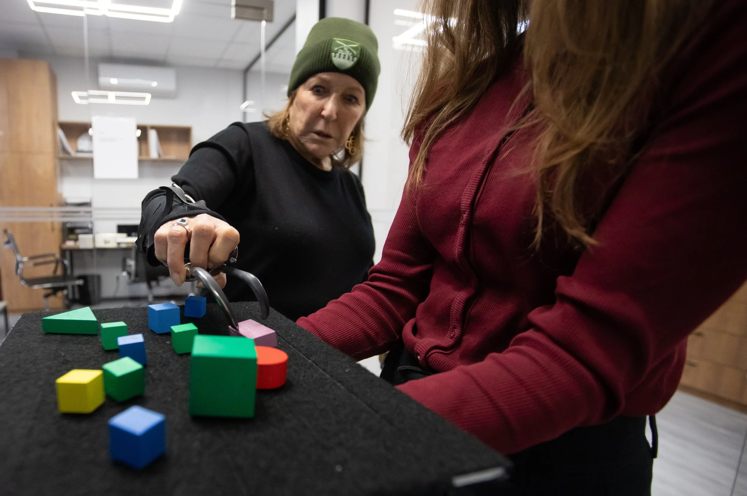 Hands On Global member Merita Callaway attempts to grab a block with a trial prosthetic Dec. 1, 2025 at the Protez Foundation in Kyiv, Ukraine.