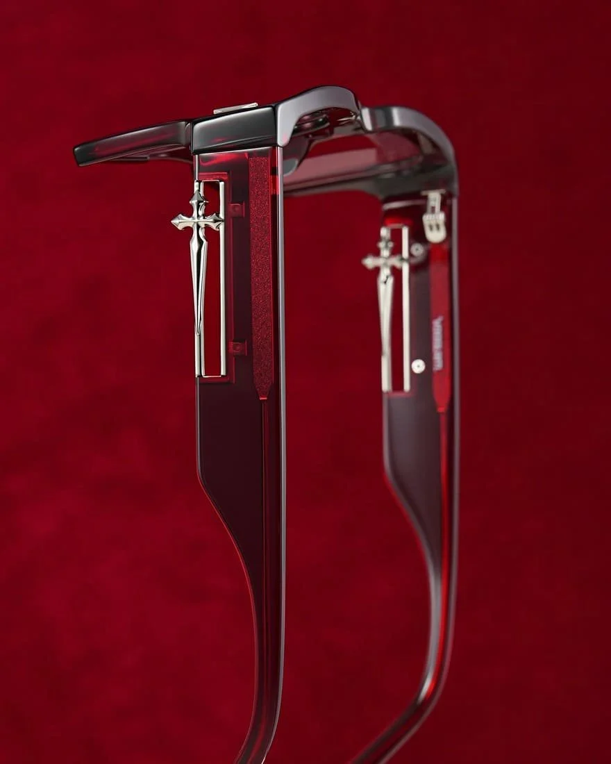 A pair of eyeglasses with black frames and silver crosses hanging from the temples, set against a deep red background.