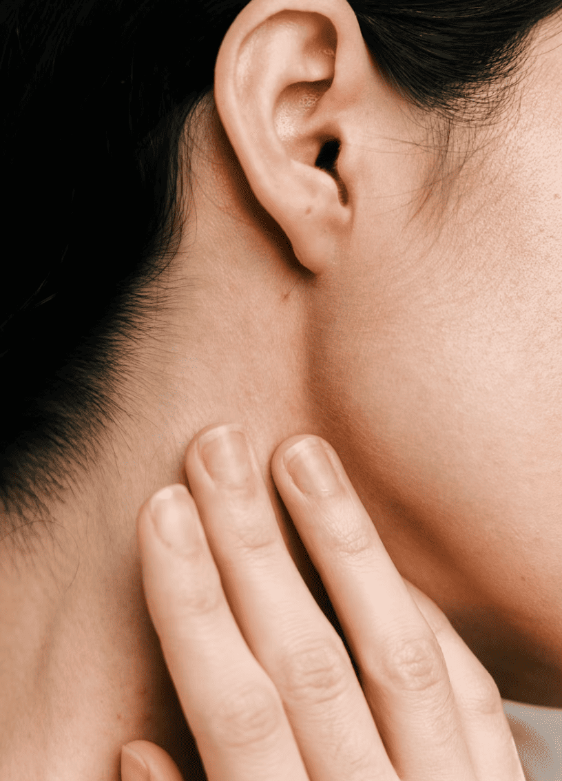 Close-up of a person's ear and neck, with fingers touching the skin near the jawline.