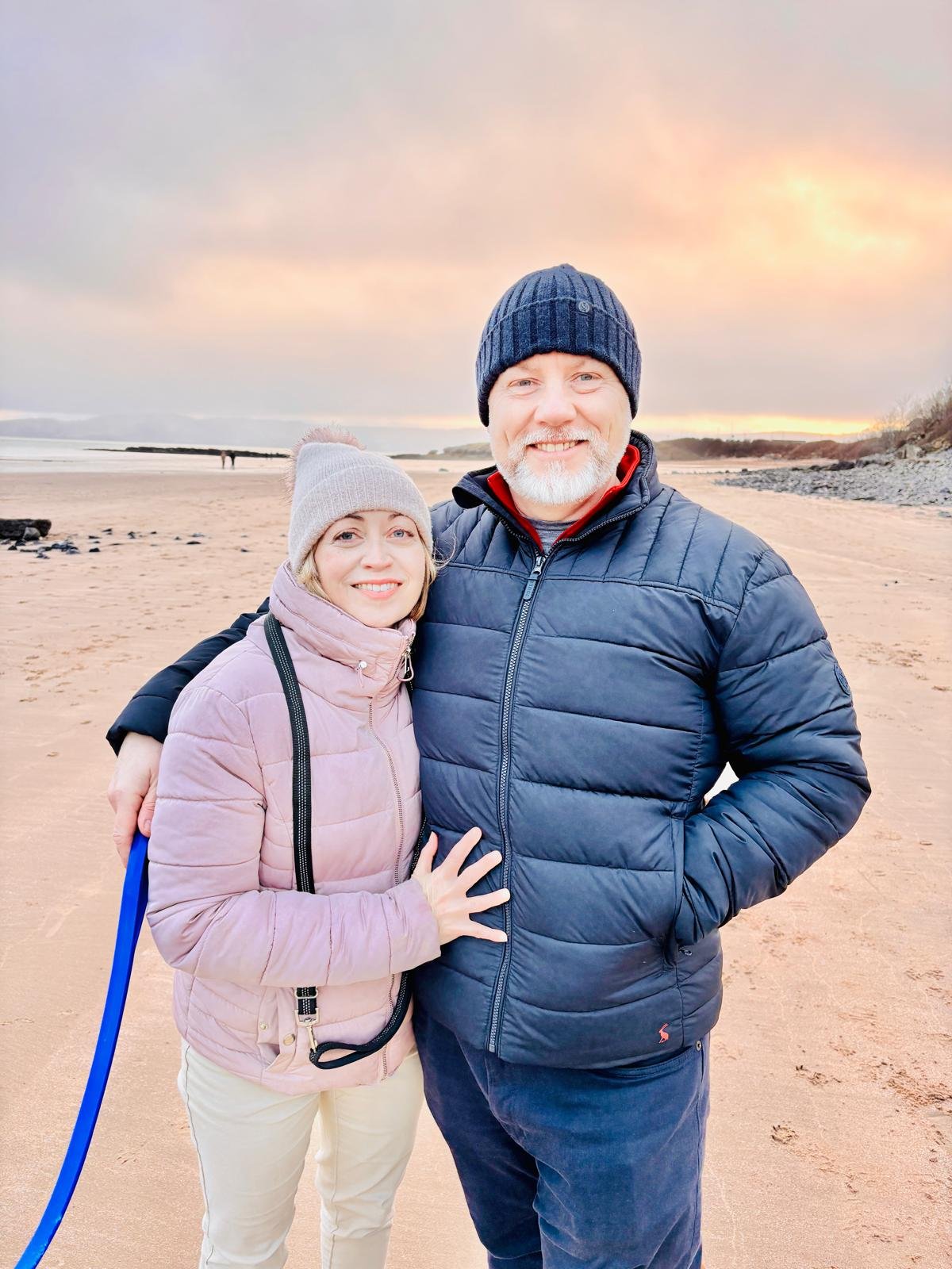 Sally and Ian, hosts of Cwtch Nook, walking their dogs on the beach in Anglesey, North Wales