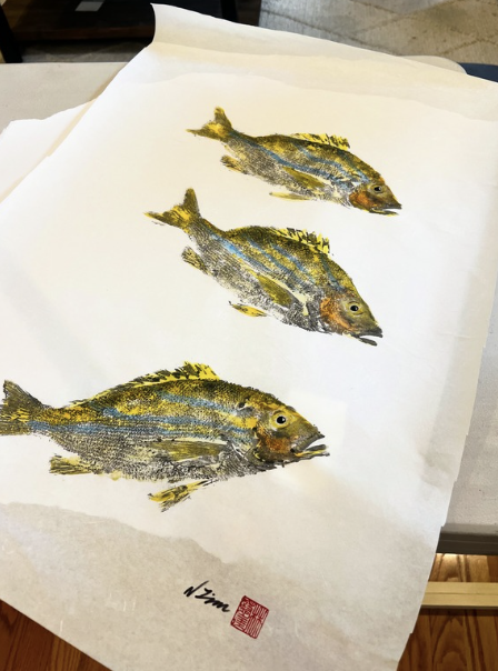 Three painted fish on white paper with red stamp and signature.