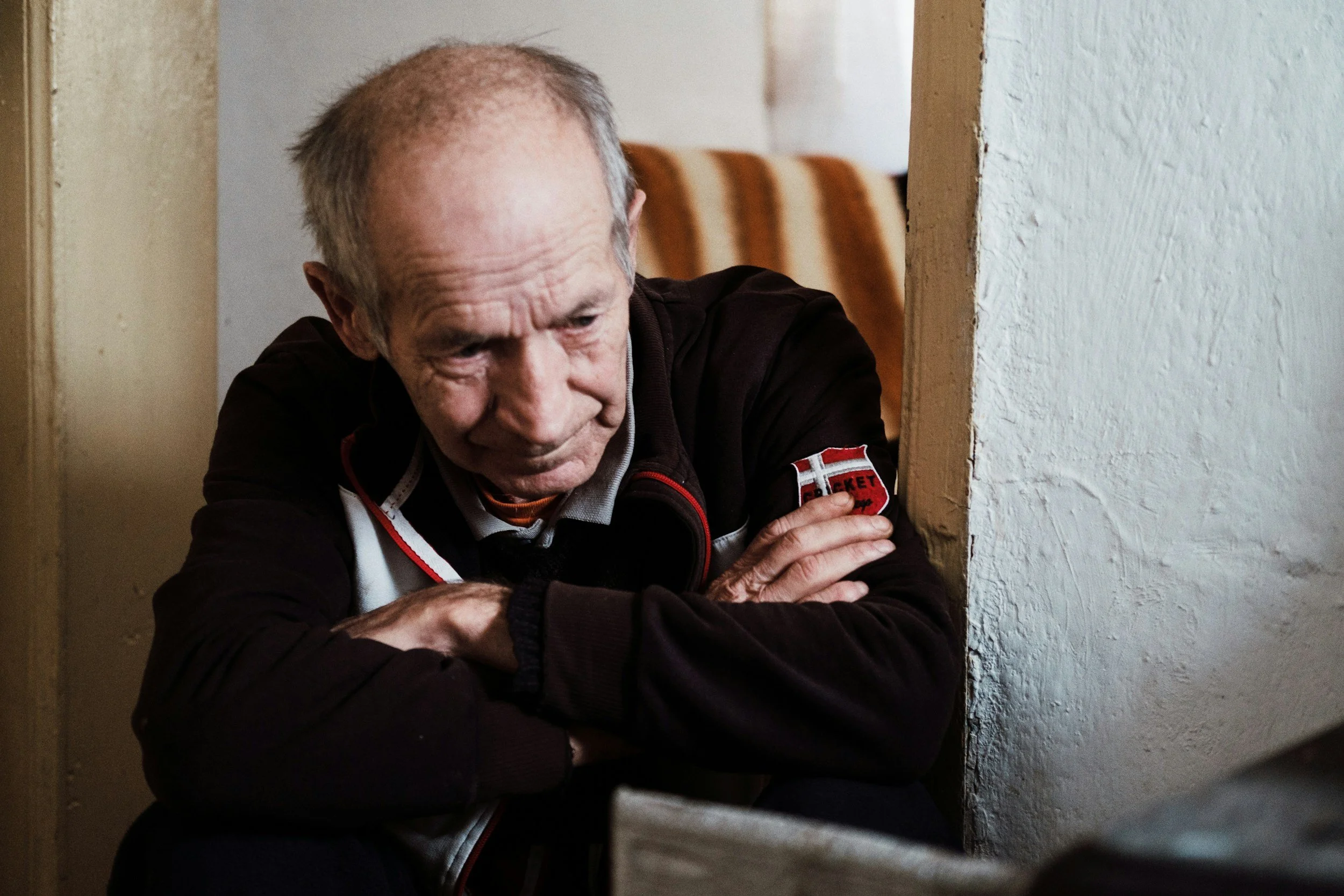 Thin elderly man wrapping his arms over his chest for warmth.