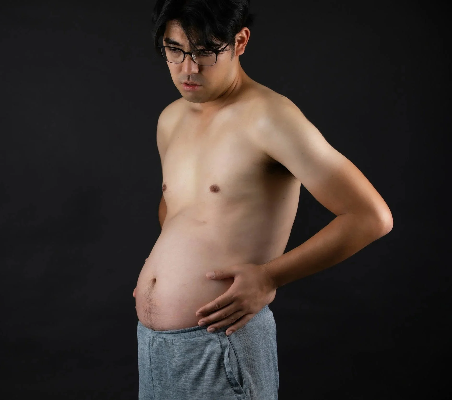 Photo of a shirtless man in sweatpants with protruding stomach