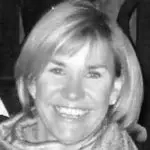 Black and white photo of a smiling woman with short blonde hair.