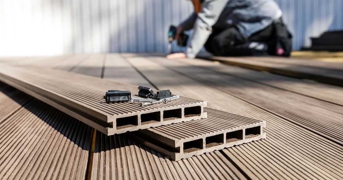 Wooden deck planks with a worker in the background installing or working on the deck.