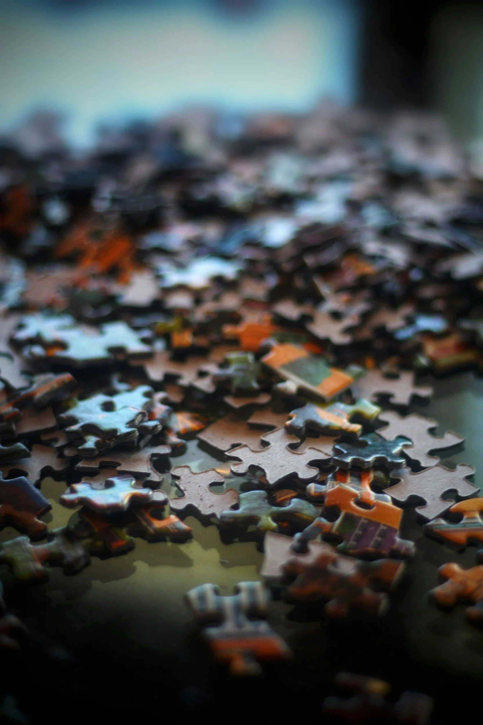 Blurred close-up of scattered jigsaw puzzle pieces on a surface.