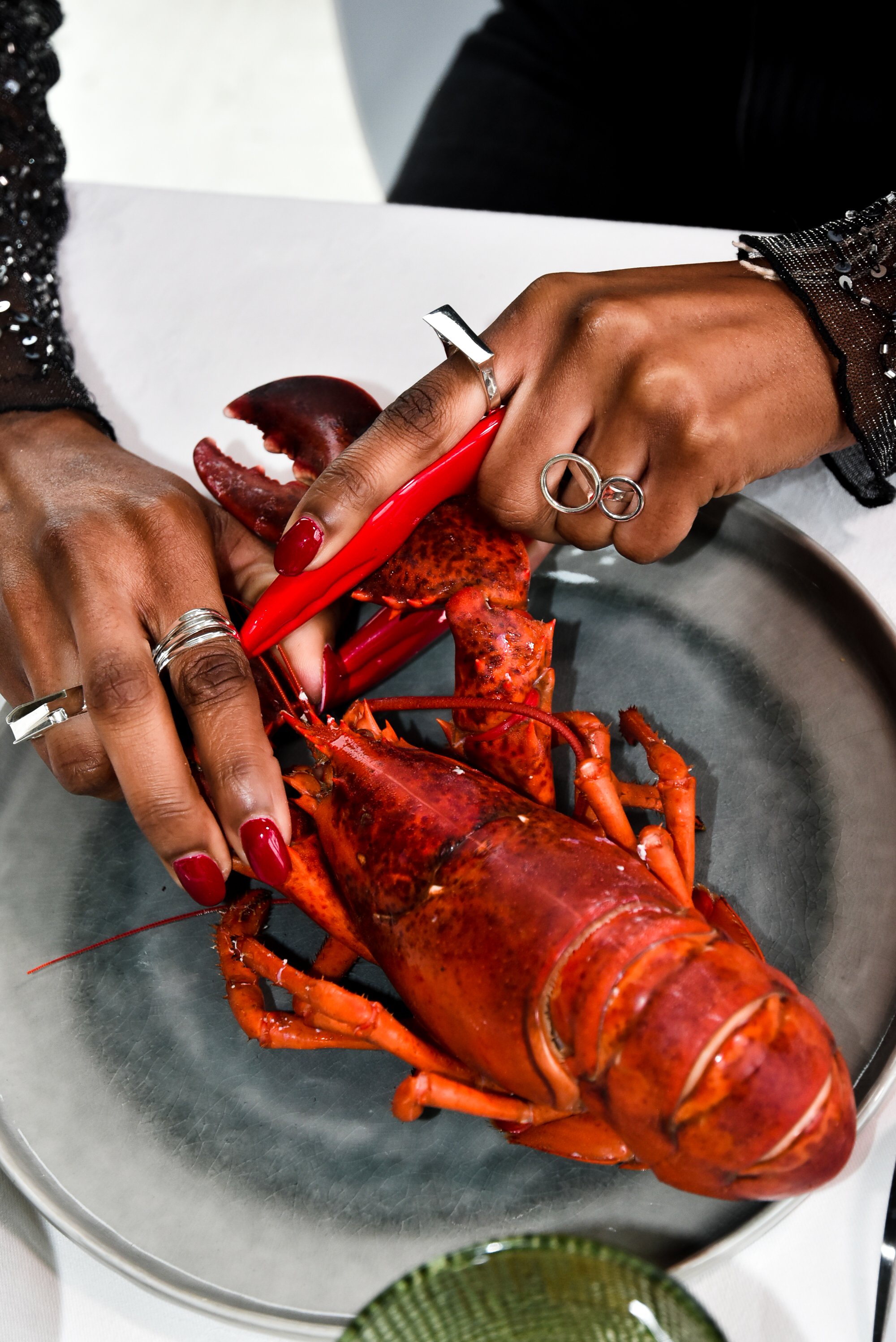 Direction artistique et shooting photo pour Mustraus : mannequin portant des bagues de créateur avec un homard pour un post social media audacieux.