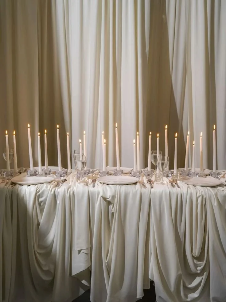 Scénographie événementielle et art de recevoir : table d'honneur avec chandelier et nappage blanc pour événement privé haut de gamme.