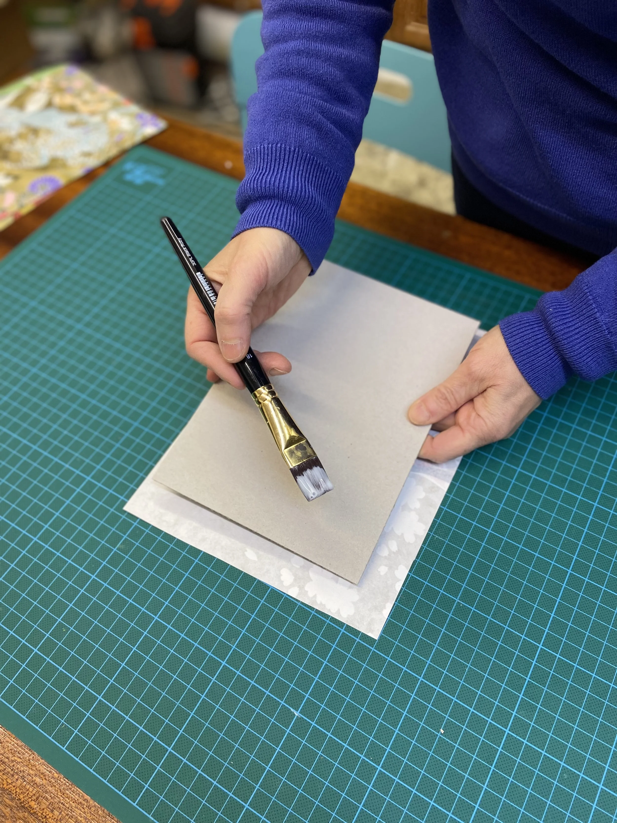 Une personne utilisant un pinceau pour appliquer de la peinture sur une feuille dans un atelier de bricolage.