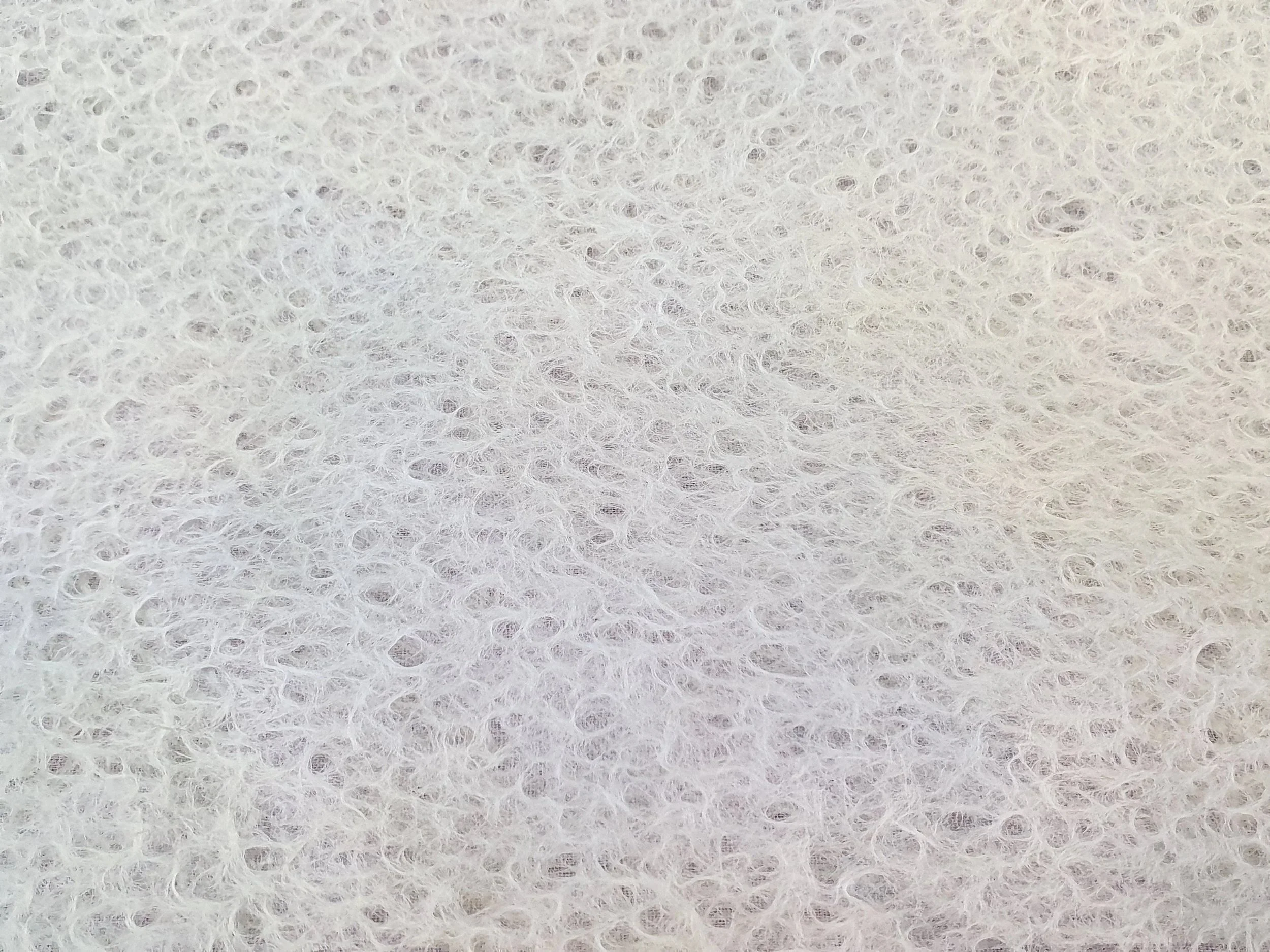 Une seule surface blanche en fibres poreuses, probablement une éponge ou un matériau de nettoyage