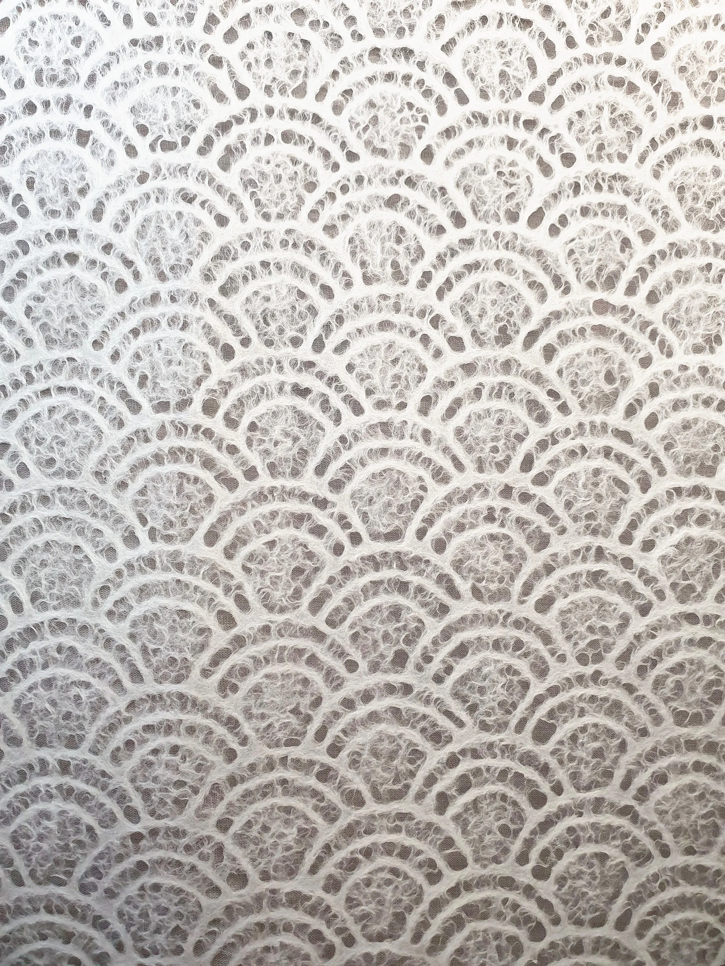 Motif de dentelle blanche avec un motif en arcs concentriques.