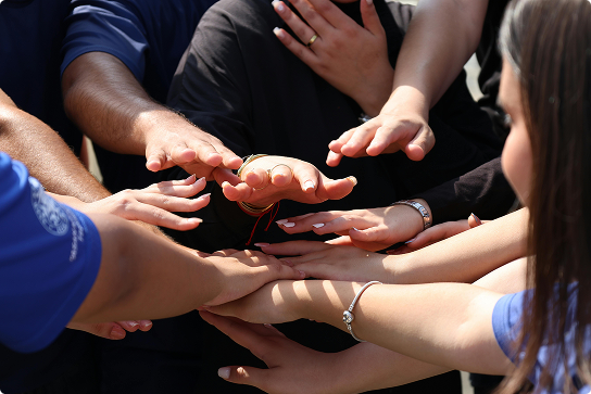 People placing hands on top of each other's in circle