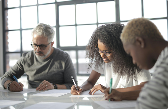 Three people at table writing