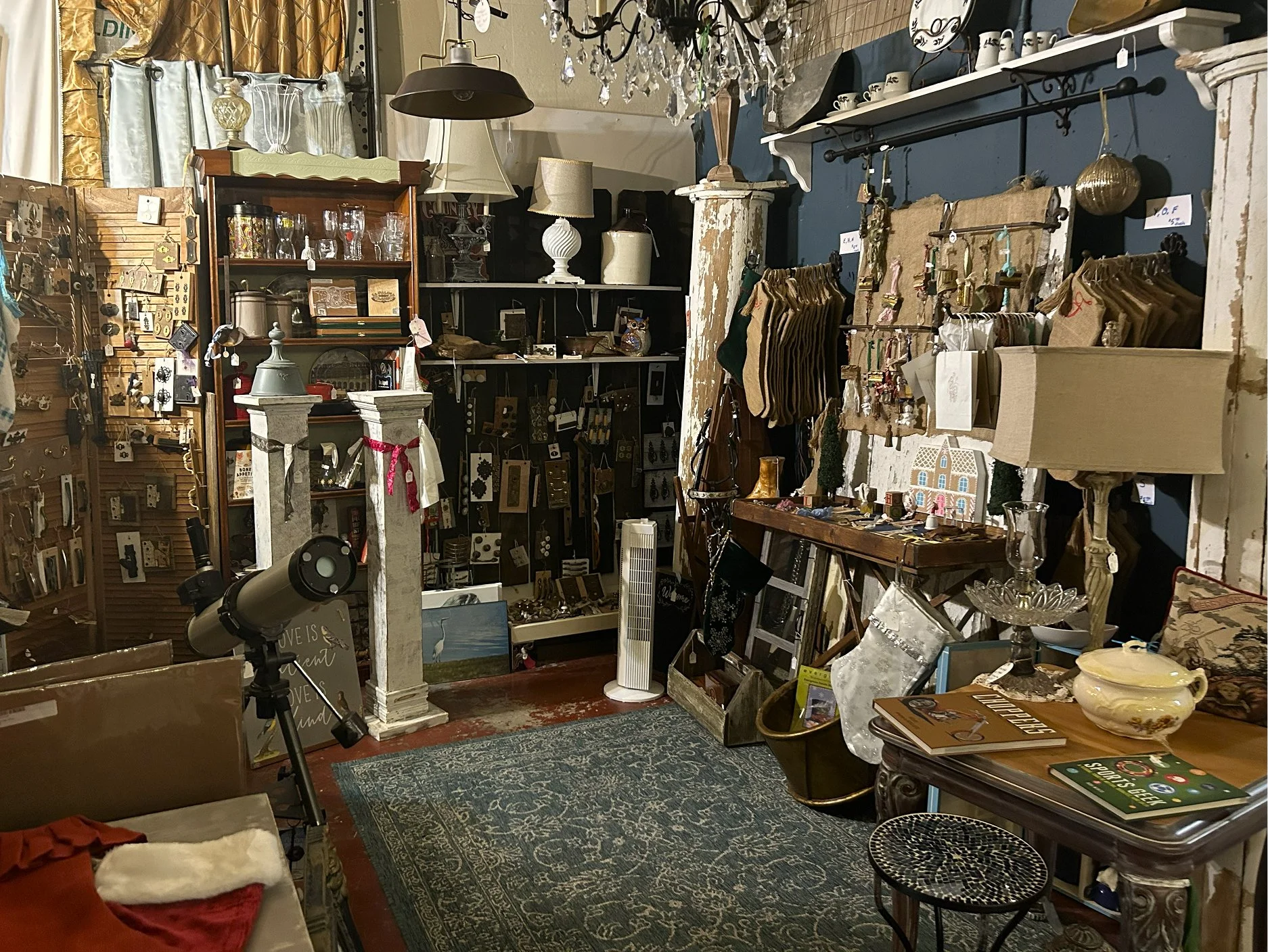A vintage store with various home decor and small decorative items displayed on shelves and tables, including lamps, picture frames, ceramics, jewelry, and Christmas stockings.