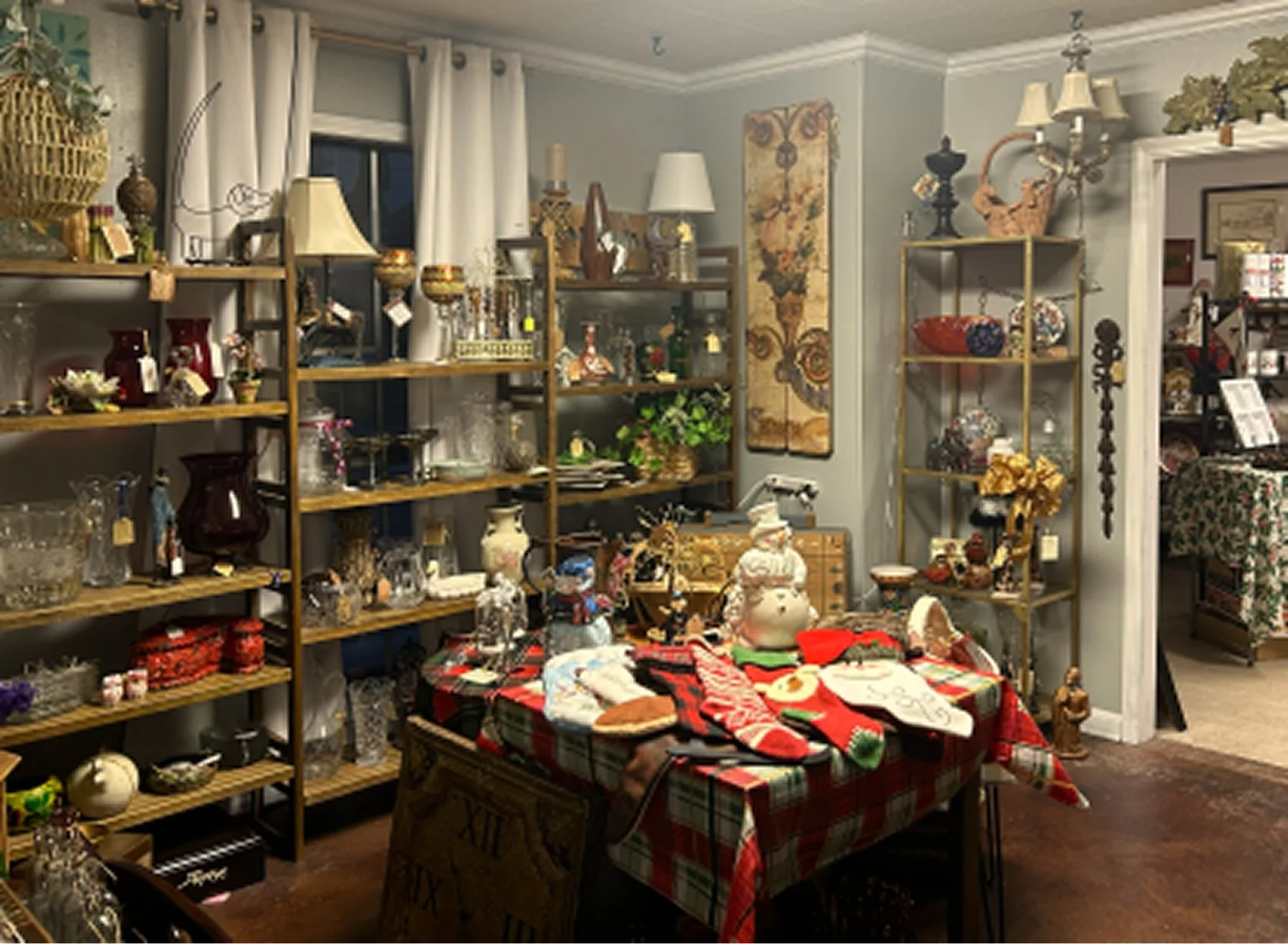 Room decorated with various ornaments and collectibles, with a table in the center covered with Christmas stockings and decorations.