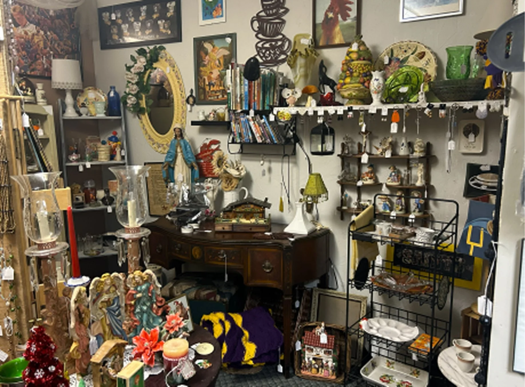 An antique store with various decorative items, artwork, and furniture including candles, figurines, shelves, and vases displayed on shelves and tables.