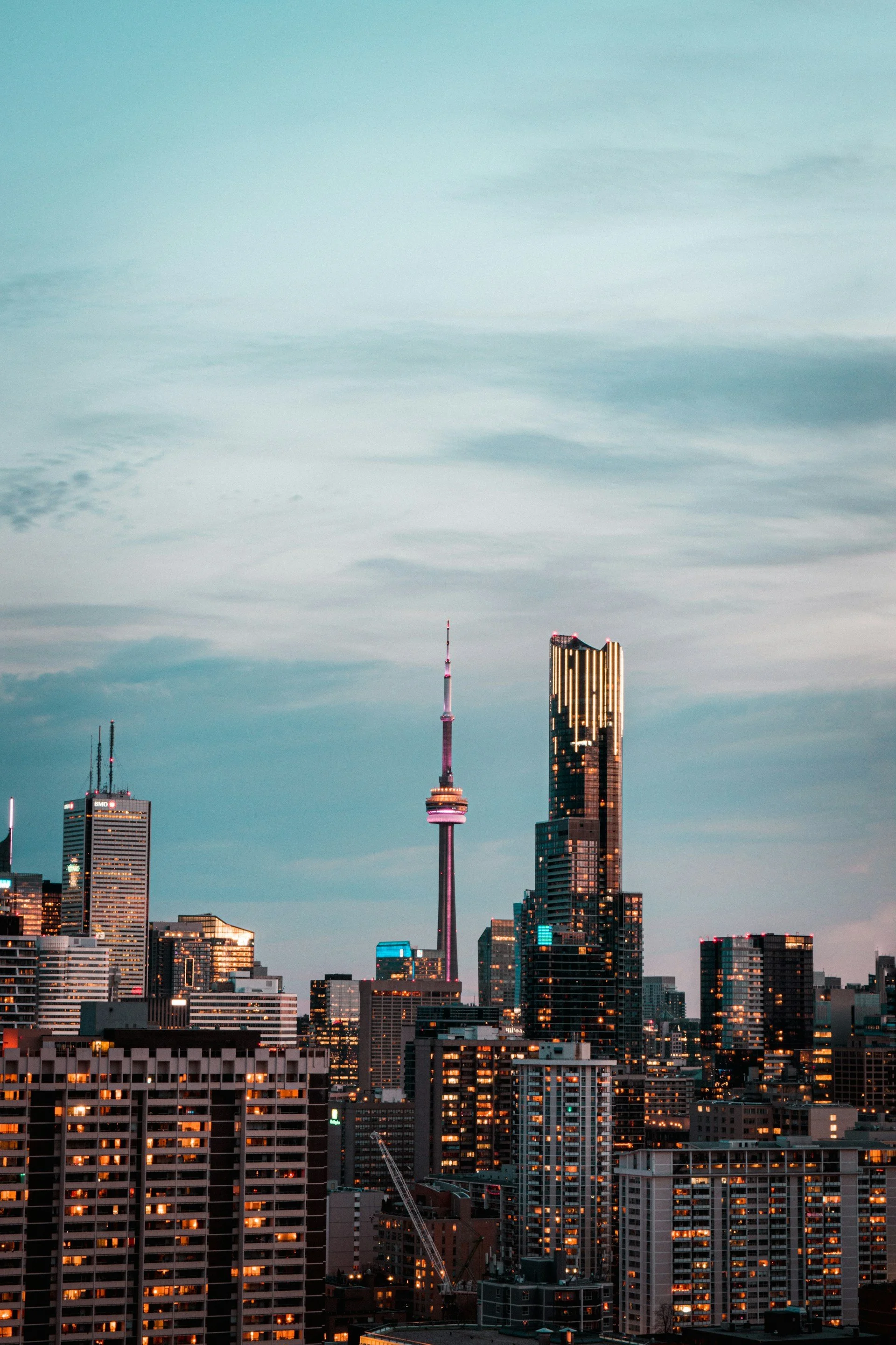 Skyline of Toronto with the CN Tower and surrounding buildings at dusk.