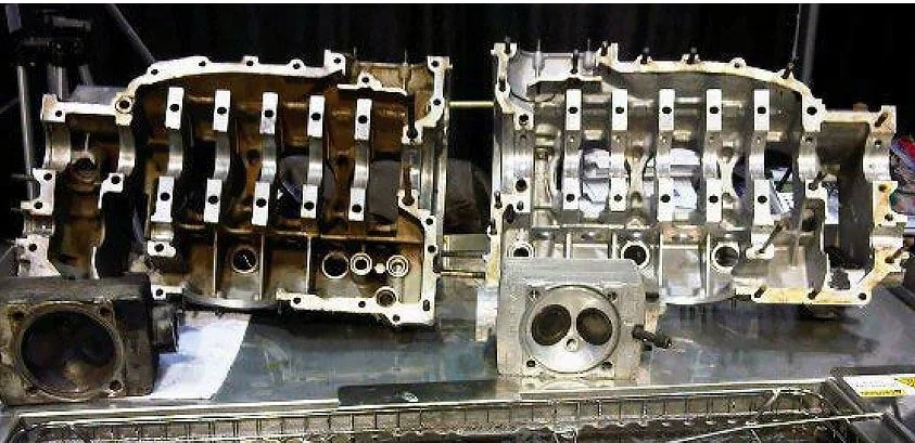 Disassembled engine cylinder heads and engine block parts on a workbench in an automotive repair shop.