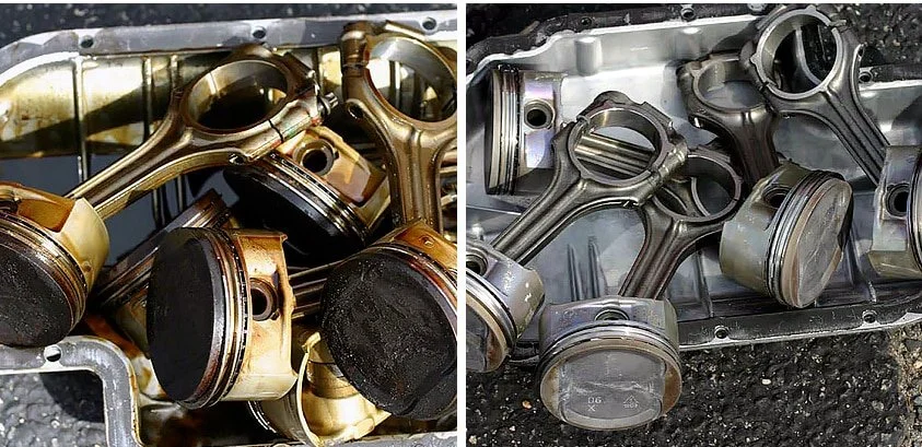 Collection of used engine pistons and connecting rods, some with carbon deposits, placed on a metal surface.
