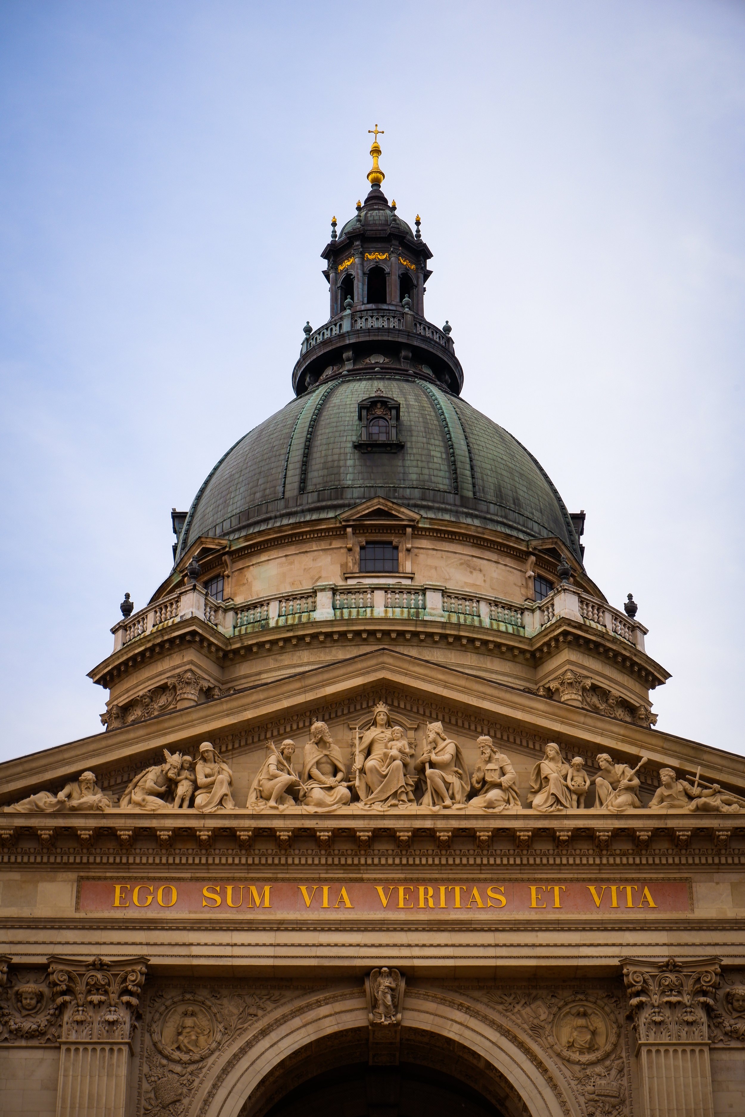 Close-up of a historic building's dome and ornate sculpture, with a Latin inscription 'EGO SUM VIA VERITAS ET VITA' on the facade.