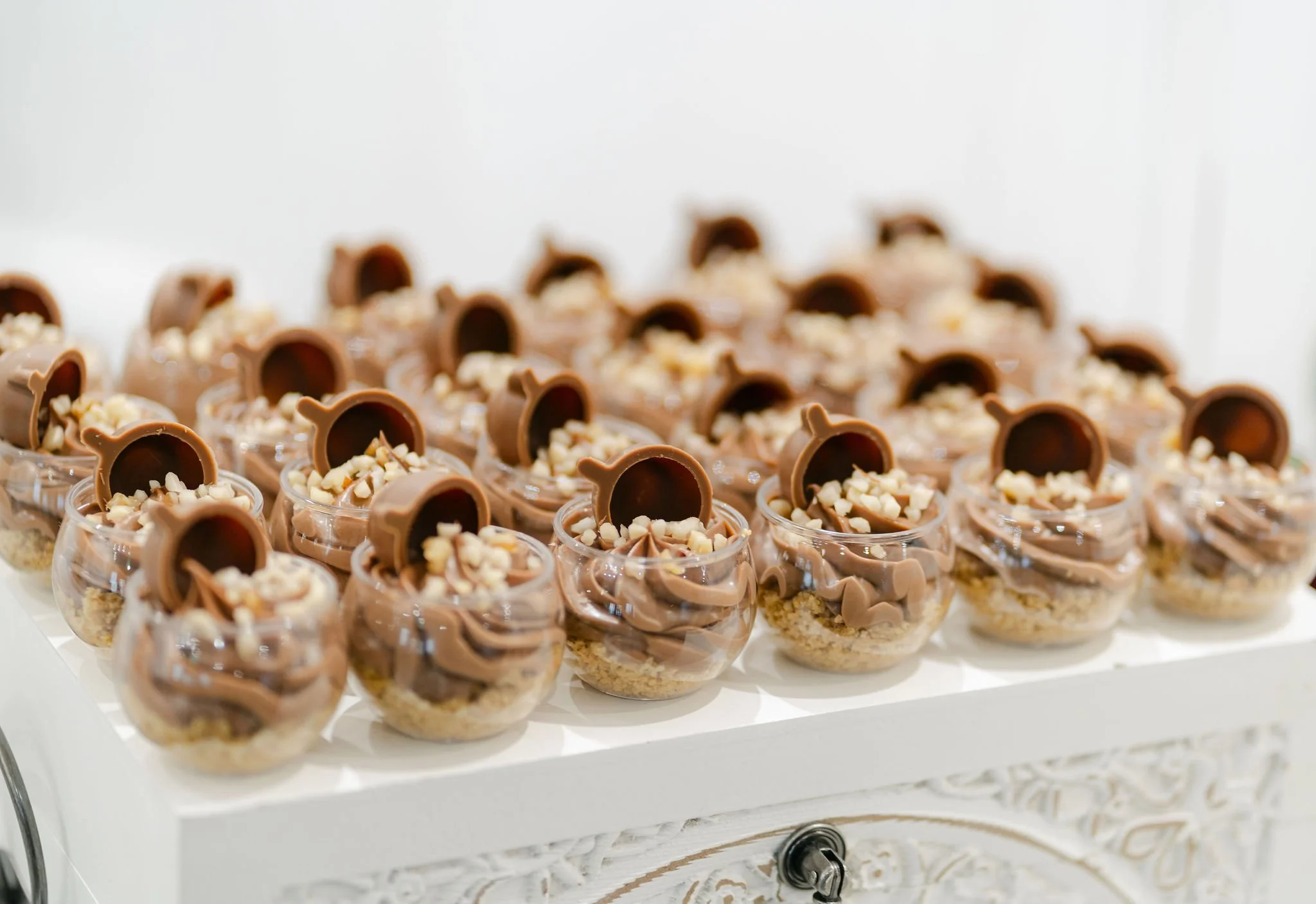 Mini dessert cups filled with chocolate mousse, topped with chopped nuts and a chocolate wafer.