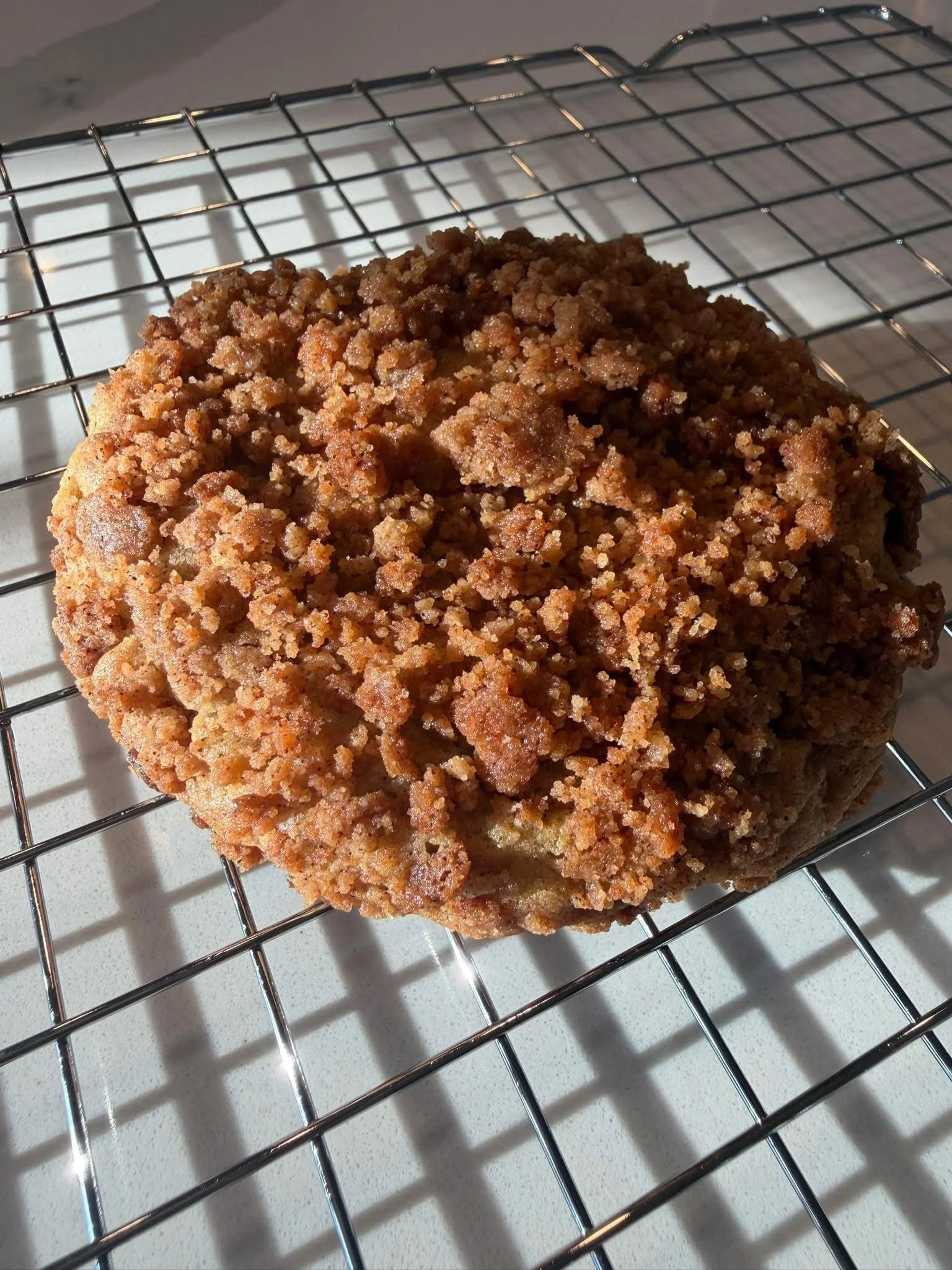 Close-up of a freshly baked crumbly coffee cake with a streusel topping resting on a wire cooling rack.