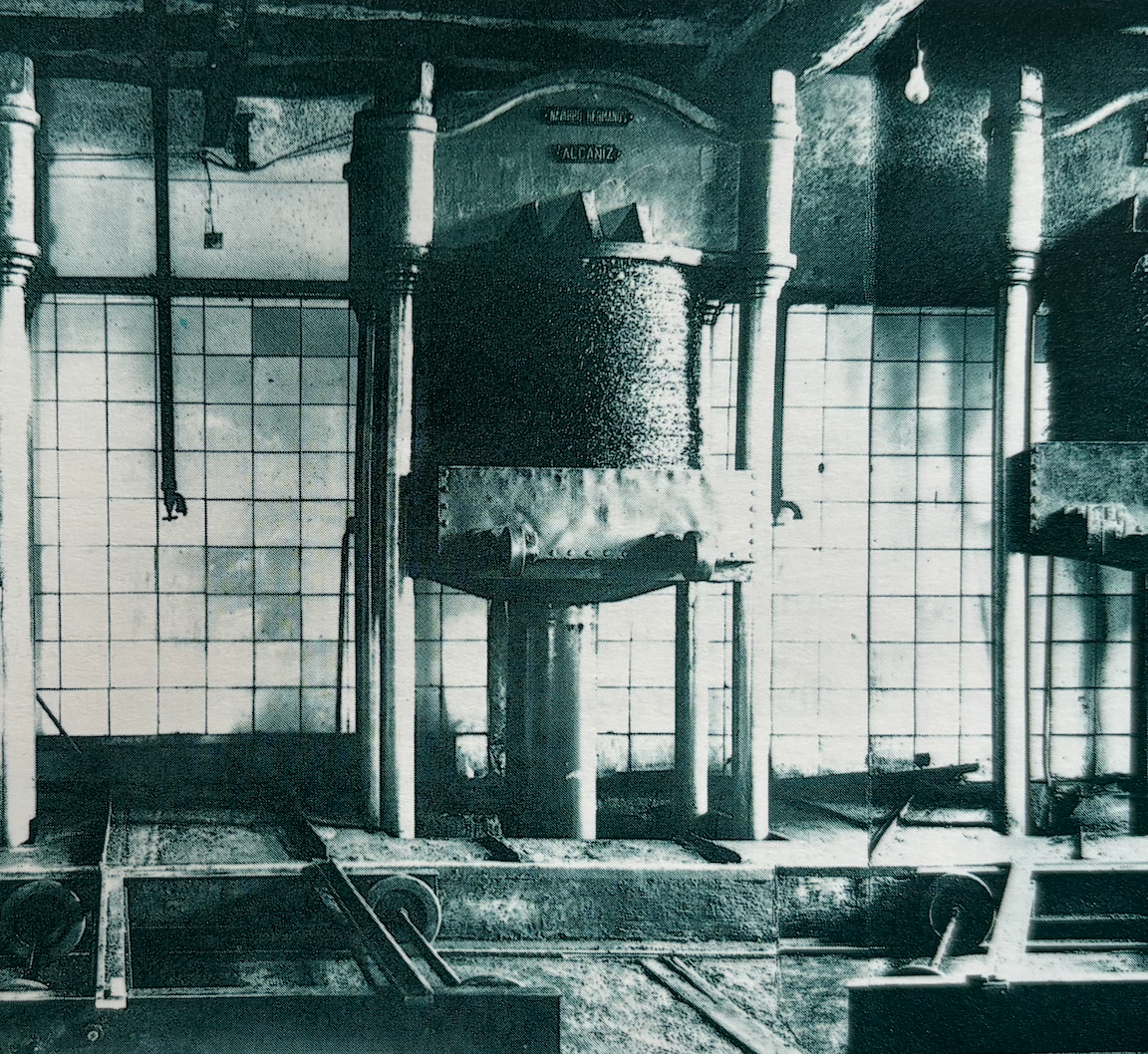 Tr Catalán, máquina de calefacción antigua en una sala con paredes de vidrio y columnas.