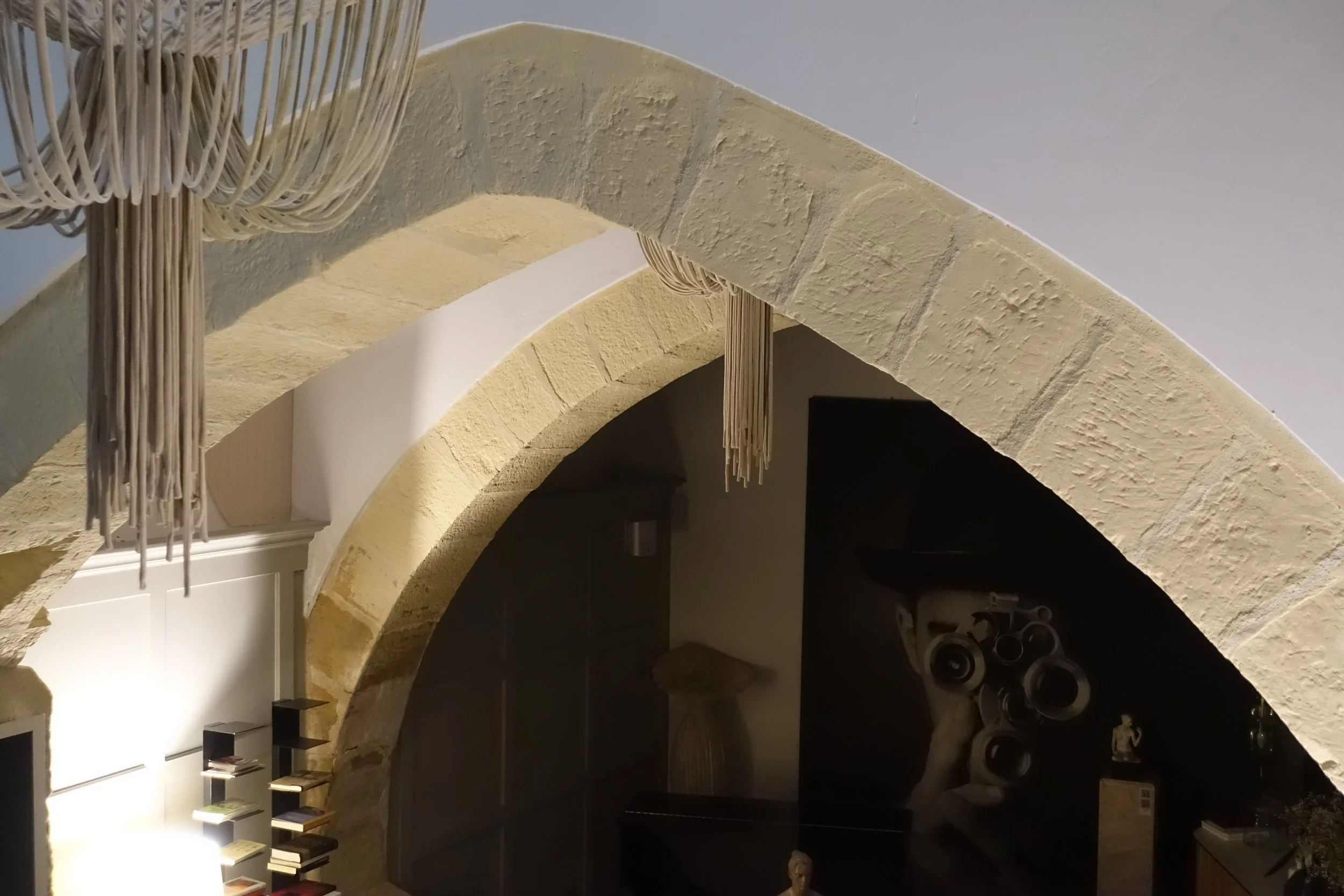 Imagen de un arco de piedra en un interior, con decoraciones y muebles oscuros a su alrededor.