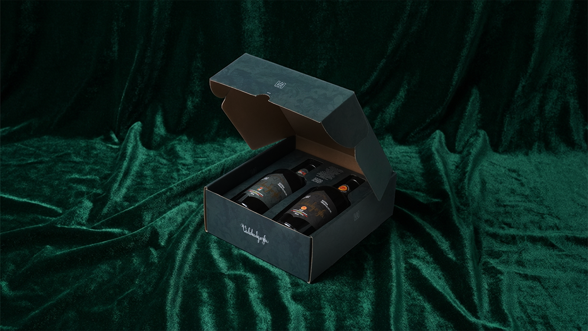 Caja abierta con dos botellas de vino contra un fondo de tela de terciopelo verde